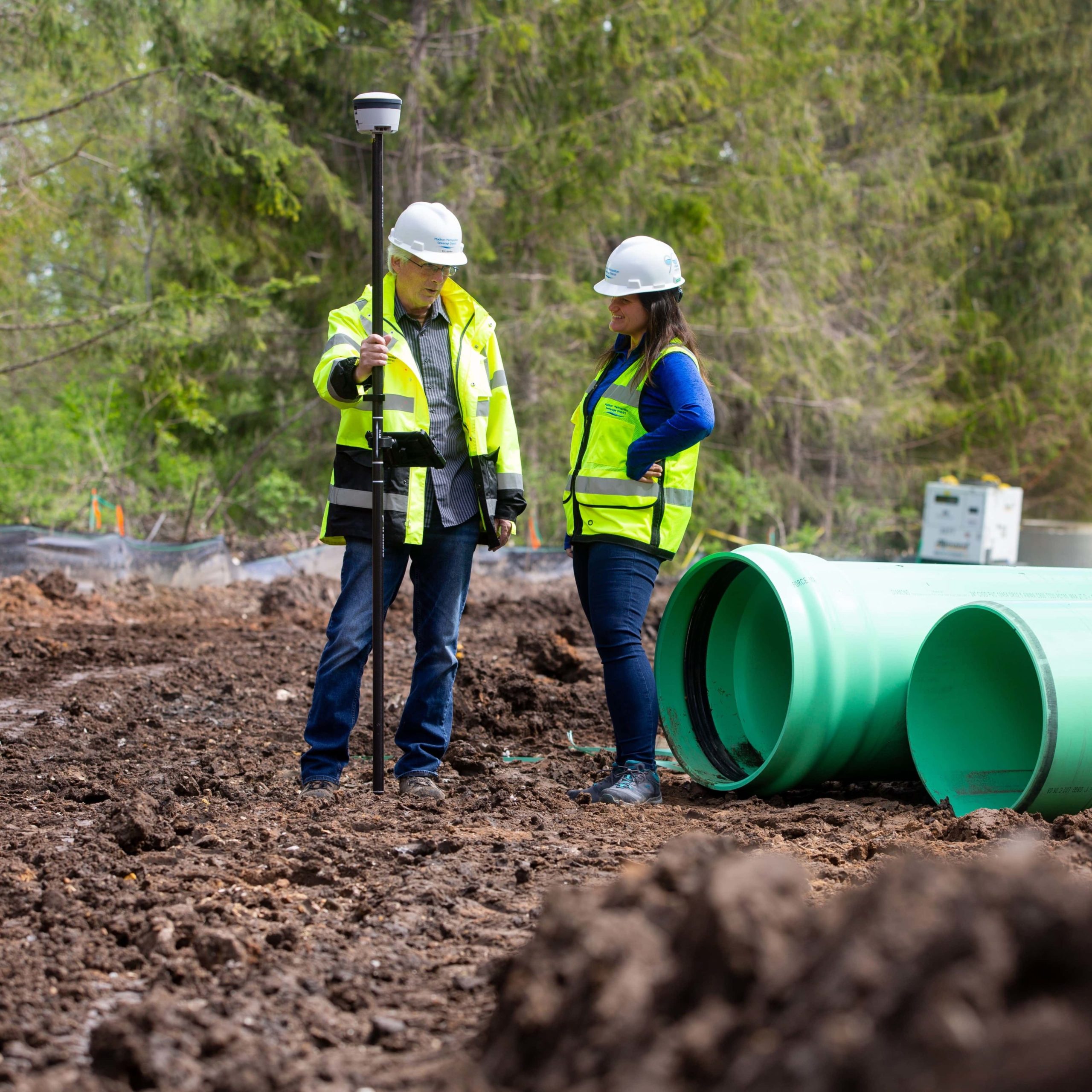 A male engineer and female worker talk on the construction job site.