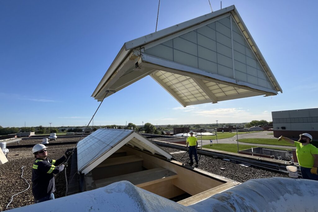 Mechanics assist the crane operator in guiding the 900-pound “doghouse” skylight back into place on the Headworks roof.