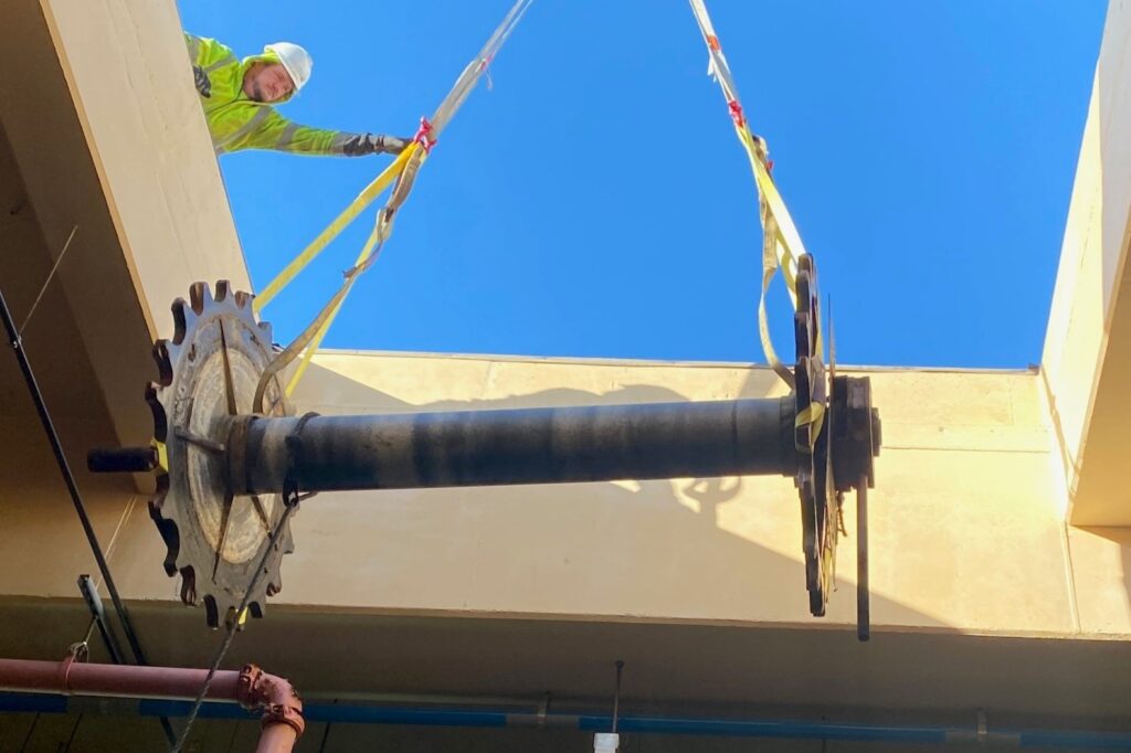 Mechanic Matt Barrett helps guide the crane’s removal of the 2,200-pound sprocket and shaft up and out through the roof opening.