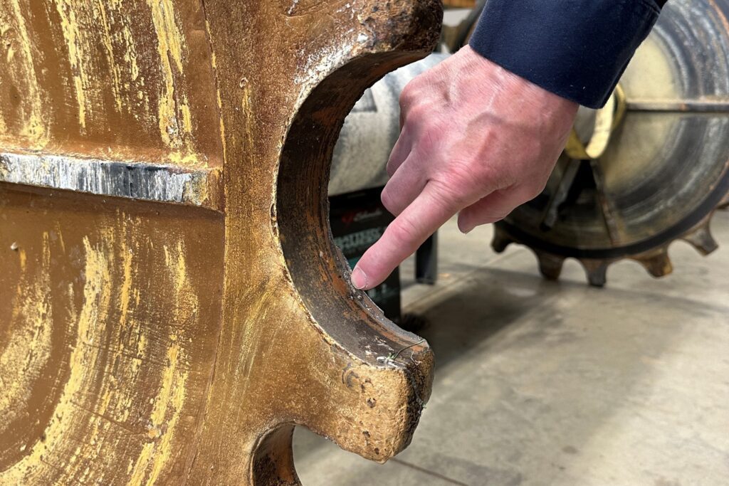 Mechanical Maintenance supervisor Jon Martinson points to the heavy wear on the old sprocket, which lasted seven years.